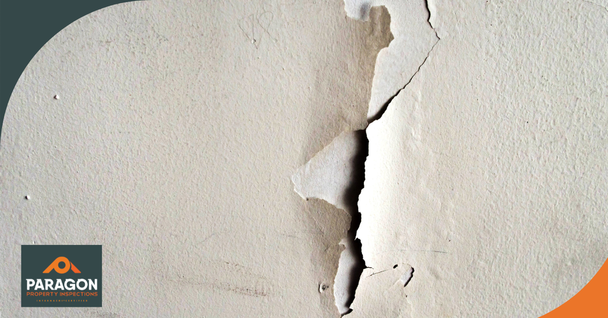 Close-up of a wall with peeling paint and visible cracks.