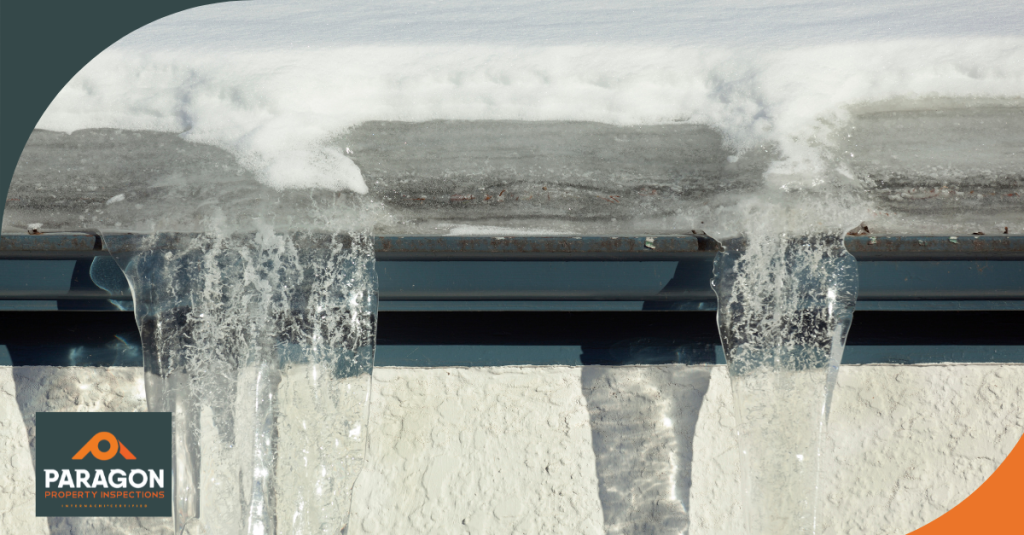 Ice buildup and frozen gutters on a snow-covered roof.